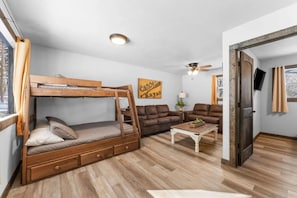 Ein gemütlicher, kleiner Wohnraum mit Etagenbett, zwei Sofas, einem Couchtisch und Deckenventilator.