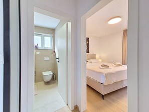 A hotel room with a bed, a bathroom, and a view of the hallway. - Apartment Cvita by Interhome (Starigrad-Paklenica)