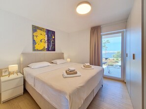 A modern bedroom with a large bed, bedside tables, a painting, and a view of the outdoors. - Apartment Cvita by Interhome (Starigrad-Paklenica)
