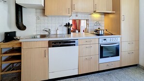 Una cocina con armarios de madera, lavavajillas, horno y fregadero.
