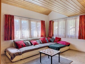 Ein gemütliches Wohnzimmer mit einer Couch, einem kleinen Tisch und einer Decke mit Holzbalken.
