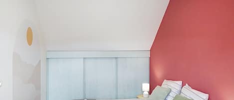 A bedroom with a bed, pillows, a nightstand, and a wall with a geometric design.
