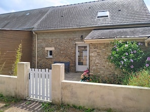 A stone house with a white gate, a small window, and a door with a glass panel. - Maison en pierre by Interhome (Pirou)
