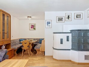 A compact living space with a kitchenette, a dining area with a wooden table and bench, and a seating area with a sofa.