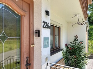 A building entrance with a wooden door, a number plaque, a small sign, and a window. - Resimini by Interhome (Pettneu am Arlberg)