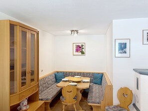 Ein kleiner Essbereich mit Holztisch und Bank, einem Schrank mit Glastüren und gerahmten Bildern an der Wand.