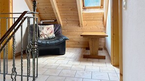 Ein Holzinnenraum mit einer schwarzen Ledersofa, einem Holztisch und einer Treppe mit Metallgeländern.