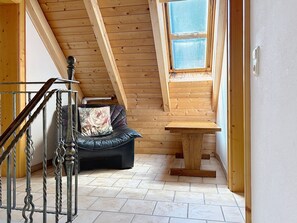 Ein Holzinnenraum mit einer schwarzen Ledersofa, einem Holztisch und einer Treppe mit Metallgeländern.
