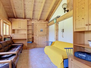 Ein Holzblockhaus-Innenraum mit einer Couch, einer gelben Decke und einer Sony Stereoanlage.