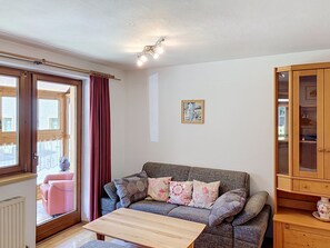 A living room with a sofa, a table, a cabinet, and a window with curtains.