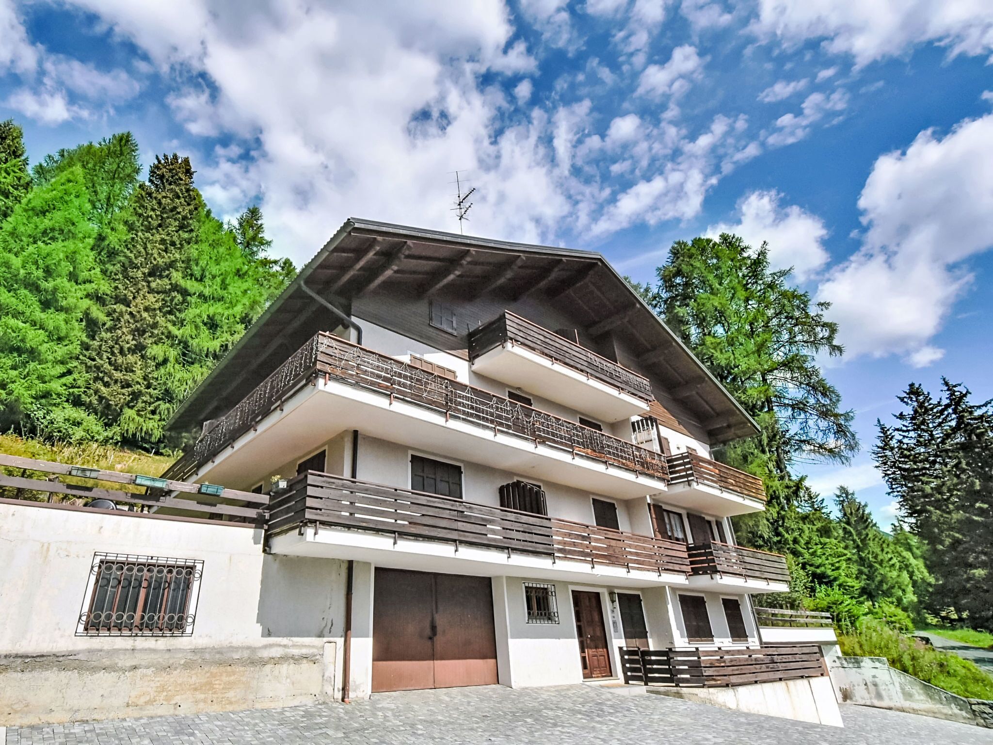 Un bâtiment à deux étages doté d’un balcon à l’étage supérieur, d’une porte de garage et d’une allée d’entrée pavée.