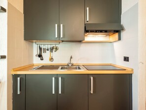 Una cuina moderna amb forn integrat, un vàter d'acer inoxidable i una varietat d'estris penjades a la paret.