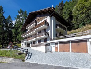 Un edifici de diverses plantes amb balcons, una calçada pavimentada i un senyal de límit de velocitat.