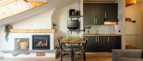 Una cocina moderna con armarios oscuros, horno empotrado y un comedor con mesa y sillas.