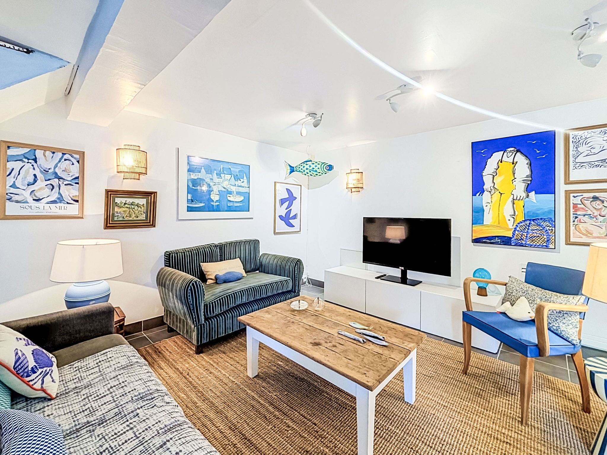 A modern living room with a sofa, a coffee table, a TV, and artwork on the walls.