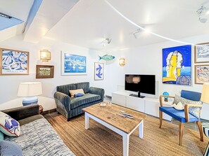 A modern living room with a sofa, a coffee table, a TV, and artwork on the walls. - La Petite Maison du Golfe by Interhome (Le Bono)