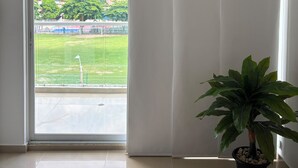 Een kamer met een grote schuifglazen deur die uitkomt op een buitenruimte. Op de vloer staat een potplant.