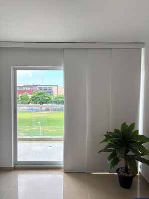 A room with a large sliding glass door leading to an outdoor area. There is a potted plant on the floor. - Amazing apartment. Prime, central location (Barranquilla)