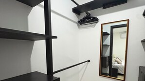 Een kamer met een zwarte wandplank, een spiegel en een bed met een witte hoofdbord.