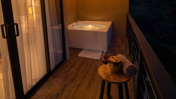 A balcony with a wooden floor, a hot tub, and string lights. - Alto Bosque. Mountain chalet with a private hot tub ⛰️🌿 (Berlín)