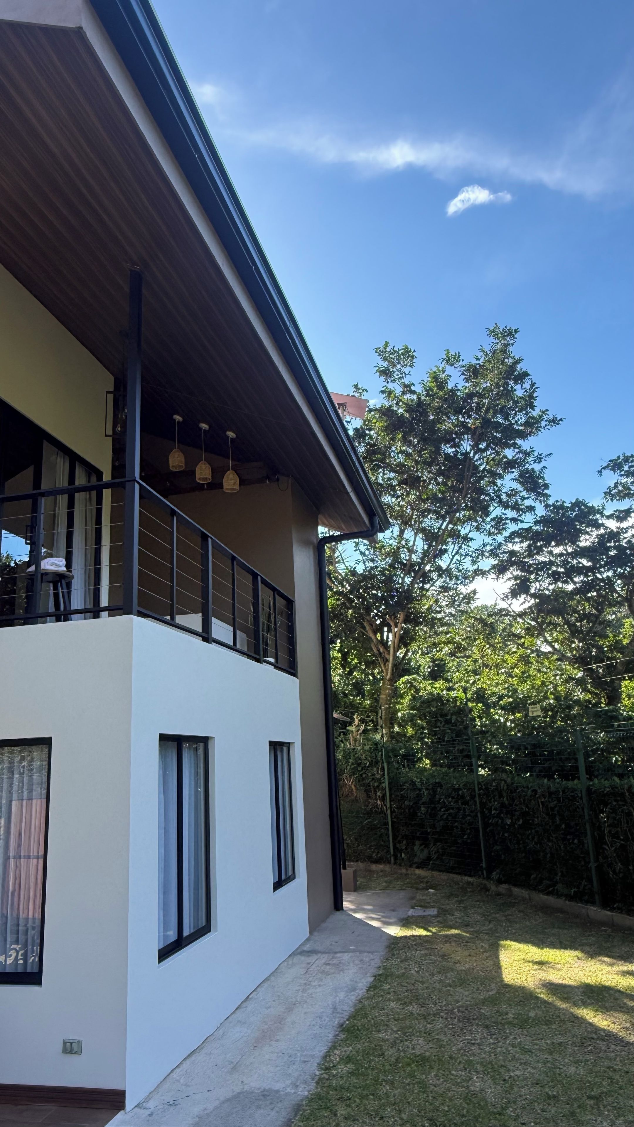 Een modern gebouw met twee verdiepingen, een balkon, grote ramen en een heldere lucht.