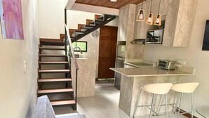 A modern kitchen with a central island, bar stools, and a staircase leading to another level. - Alto Bosque. Mountain chalet with a private hot tub ⛰️🌿 (Berlín)