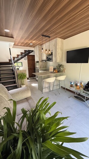 A modern kitchen with a central island, bar stools, and pendant lighting.