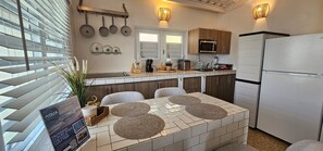 A modern kitchen with a central island, white refrigerator, and wooden cabinets.