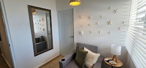 A hallway with a mirror, starfish wall decor, a grey sofa with cushions, a small table with a lamp, and a window with blinds. - Private Beachfront Estate w/ Infinity Pool (Santa Isabel)