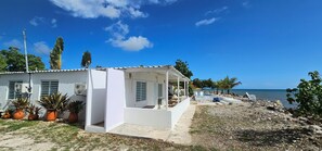 A white building with a covered patio, potted plants, and a view of the sea. - Private Beachfront Estate w/ Infinity Pool (Santa Isabel)