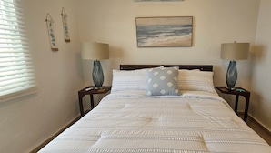 A bedroom with a bed, two nightstands, a lamp on each nightstand, a painting above the bed, and a window with blinds. - Private Beachfront Estate w/ Infinity Pool (Santa Isabel)
