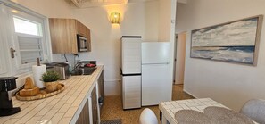 A compact kitchen with a microwave, sink, and refrigerator. There is a small dining area with a table and chairs. - Private Beachfront Estate w/ Infinity Pool (Santa Isabel)