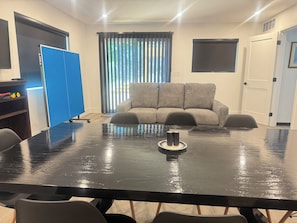 A conference room with a large black table, grey sofa, and a blue partition.