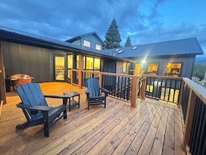 A wooden deck with outdoor seating and a staircase leading to an upper level.