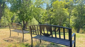 Deux bancs de parc situés dans un cadre naturel, avec des arbres et de l’herbe.