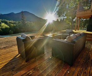 Eine Terrasse mit Korbmöbeln und einem Feuerkorb, mit Blick auf eine gebirgige Landschaft.