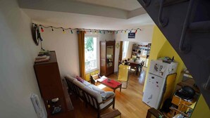 Et flerplans opholdsrum med sofa, spisebord og et køkkenområde.