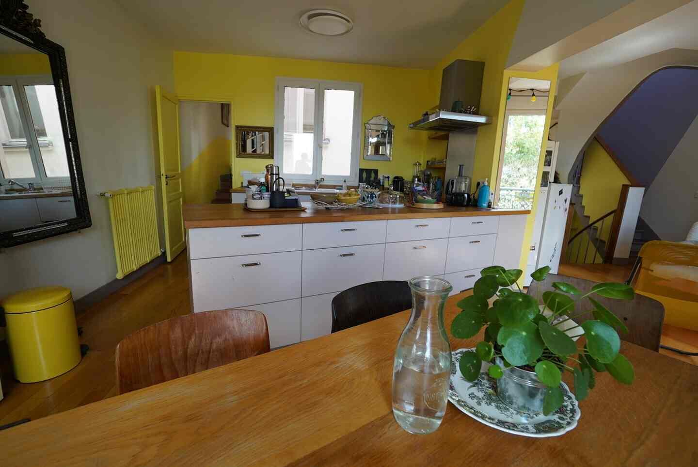 Una cocina con una mesa de madera, un florero y una planta en maceta.