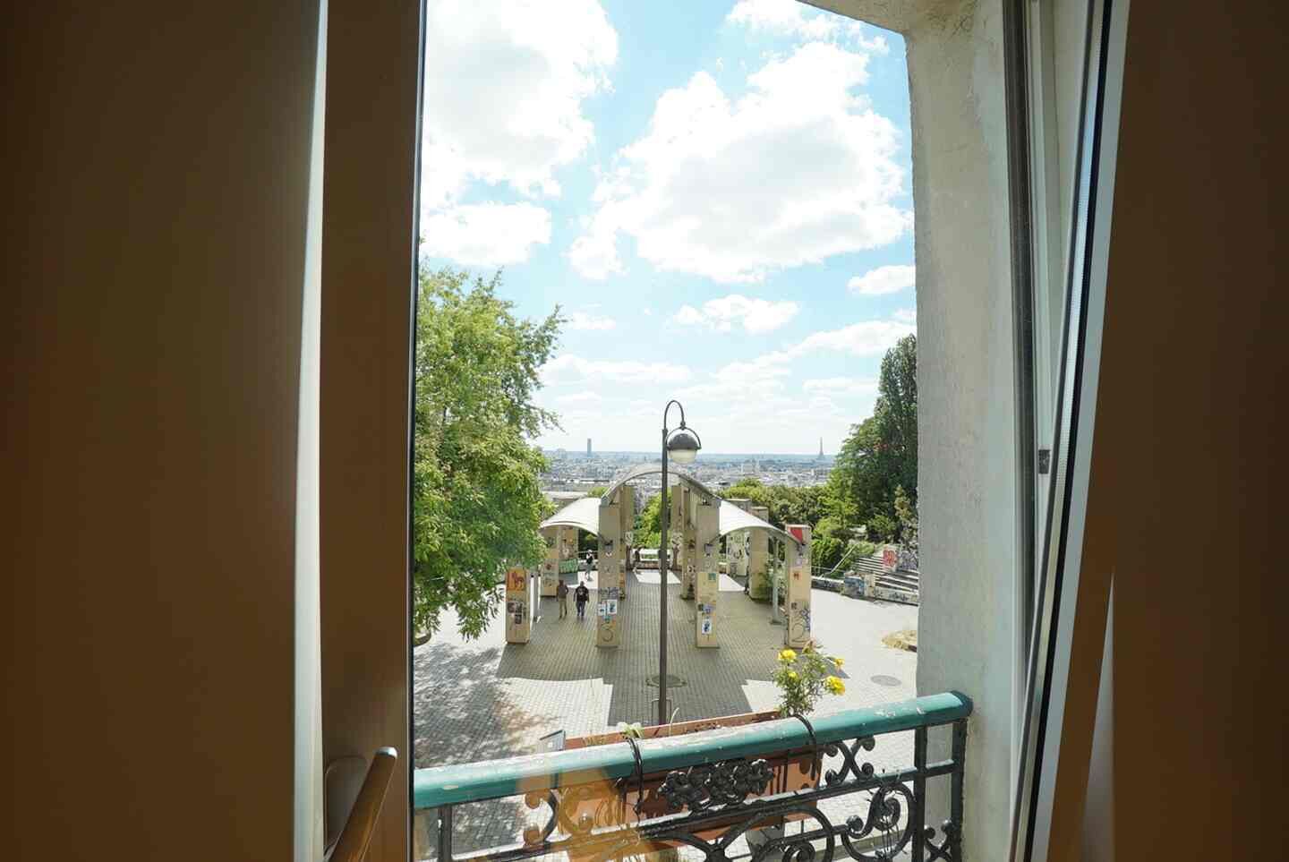 Een balkon met uitzicht op een stadslandschap, inclusief een toren in de verte.