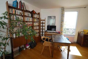 A study room with a wooden desk, a bookshelf, a computer, and a window with a view. - Bright apartment with a view of all of Paris, 5 rooms, 3 levels, feels like a house, Belleville (Paris)