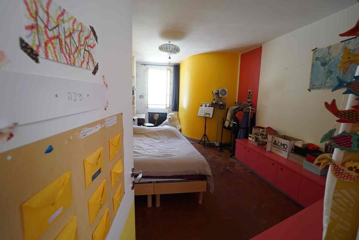 A room with a bed, a desk, a lamp, and a wardrobe.