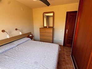 A bedroom with a bed, a dresser, a mirror, and a door. - 4-bedroom house in a gated community with a pool and beaches just 5 minutes away (Alcalà de Xivert)