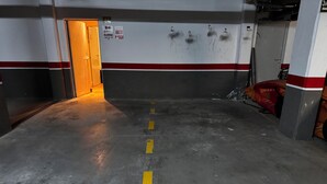 Autotalli, jossa on betonilattia, merkityt parkkipaikat ja ovi, joka johtaa toiselle alueelle.
