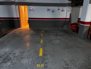 A parking garage with a concrete floor, marked parking spaces, and a door leading to another area. - 4-bedroom house in a gated community with a pool and beaches just 5 minutes away (Alcalà de Xivert)