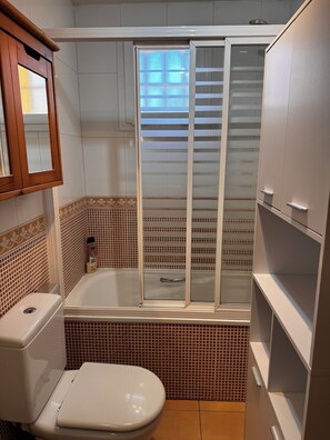 A bathroom with a toilet, a shower enclosure, and a cabinet. - 4-bedroom house in a gated community with a pool and beaches just 5 minutes away (Alcalà de Xivert)