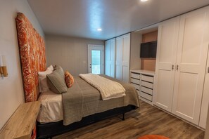 A bedroom with a bed, bedside tables, a wardrobe, a television, and a window with blinds. - 4 BR, 3 bath ranch home featuring 2 King & 2 Queen bedrooms  (Sioux Falls)