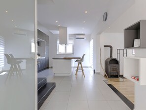 A modern kitchen with a built-in stove, a dining area with a table and chairs, and a large window providing natural light. - Vacation home A.E.M by Interhome (Medulin/Šišan)