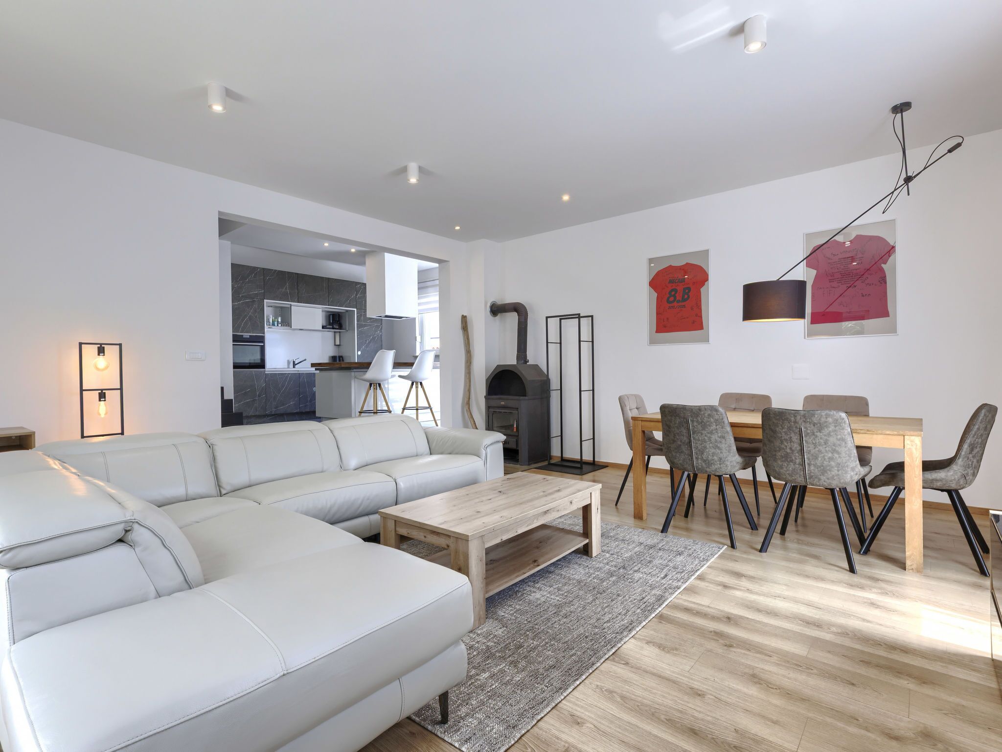 Un salon moderne avec un canapé blanc, une table basse en bois et un coin repas comprenant une table et des chaises.