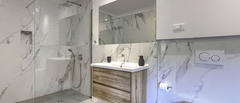 A modern bathroom with a glass-enclosed shower, a wooden vanity, and a toilet.