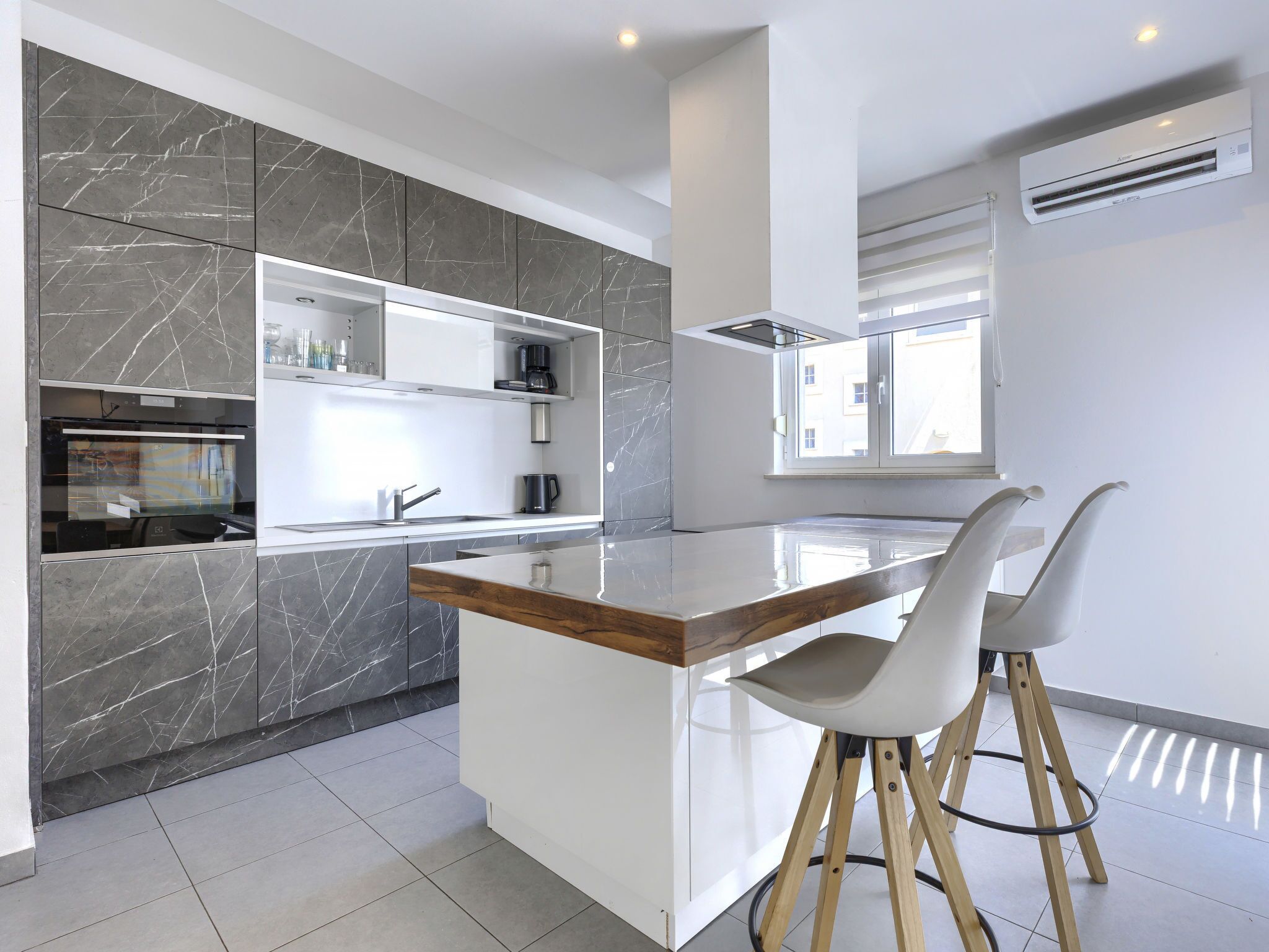 Een moderne keuken met een marmeren spatwand, een centraal eiland en een ingebouwde oven.